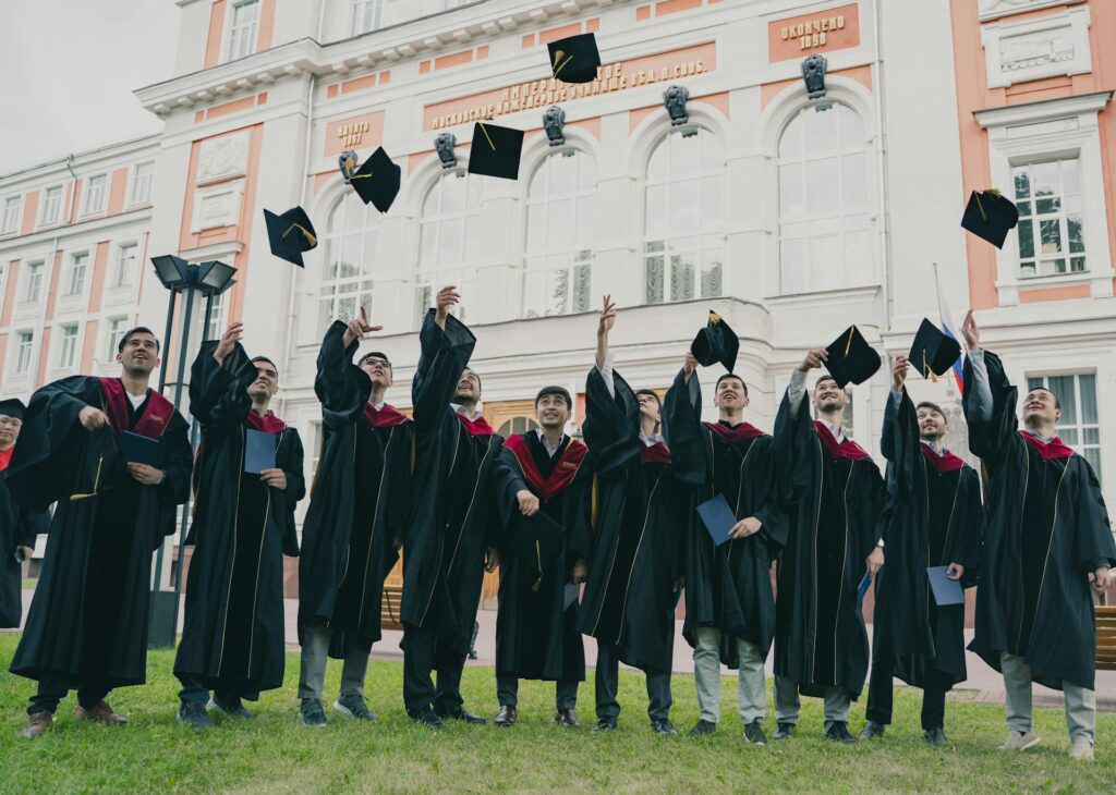 Graduates in gowns holding their caps up