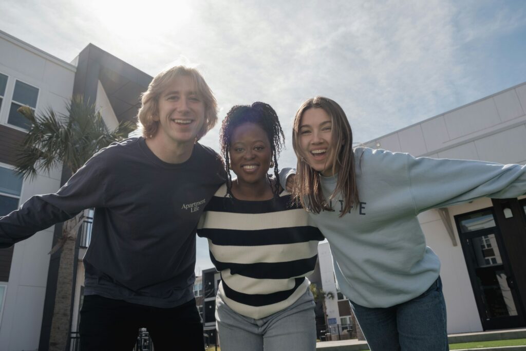 Three smiling friends with their arms around each other