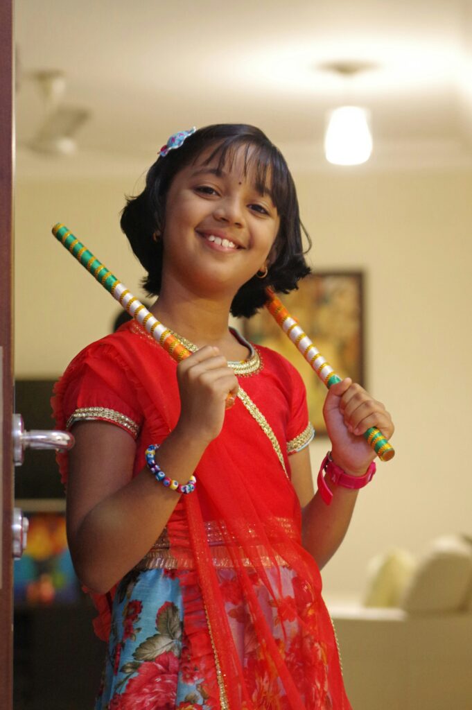 A little girl in traditional dress ready for garba with dandiya sticks
