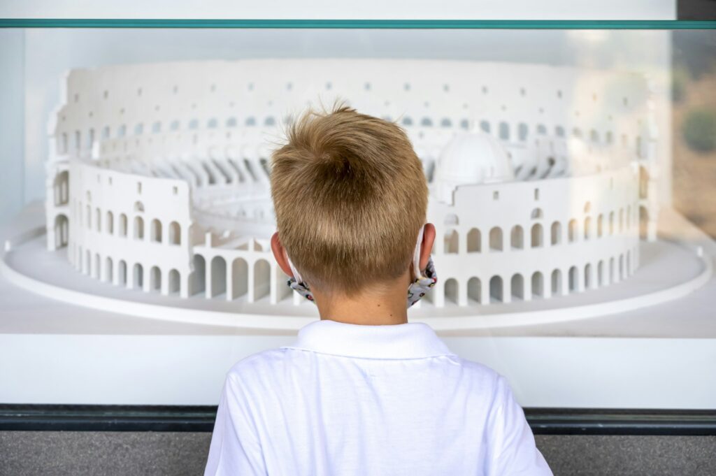 A boy studying a model of an ancient monument in a museum