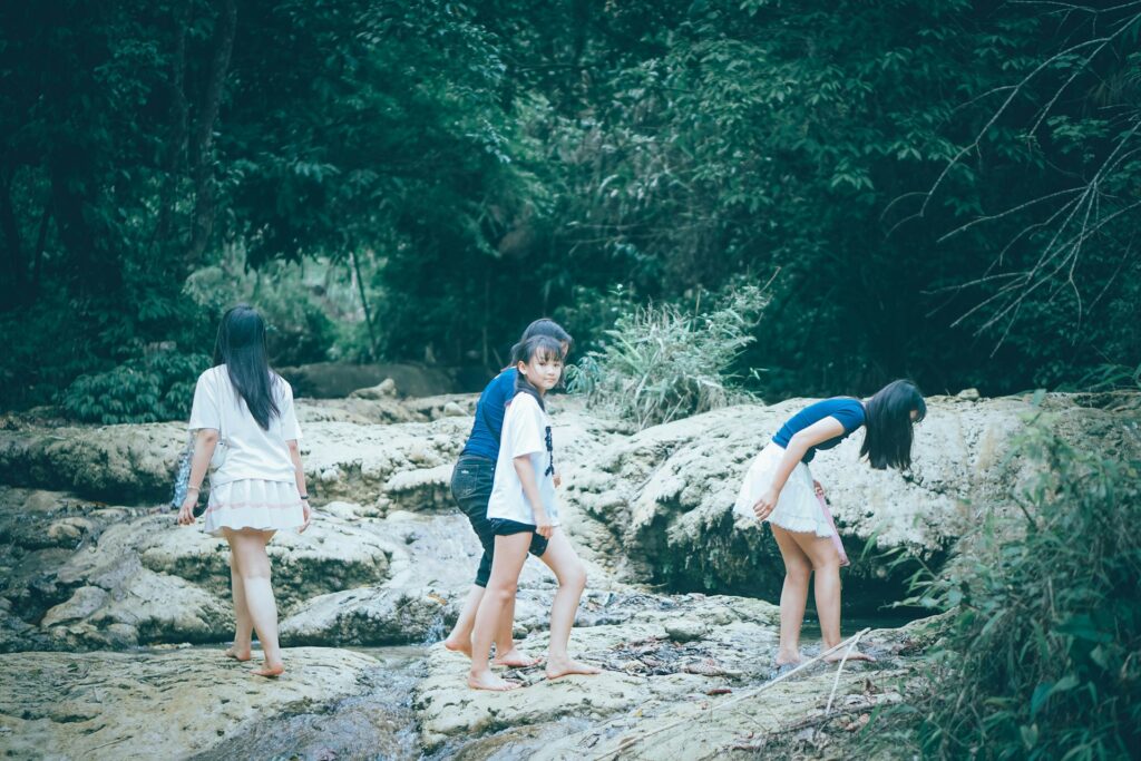 Three girls exploring beside a rocky stream